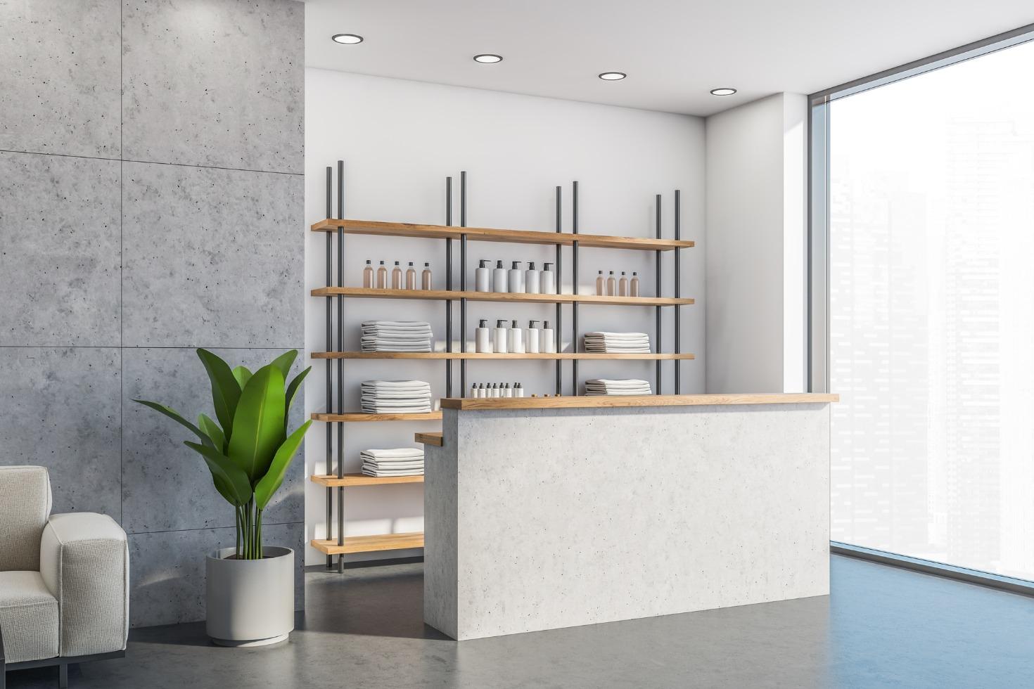 The grey interior of a modern spa reception area. A plant sits in a pot to the side of the reception desk.