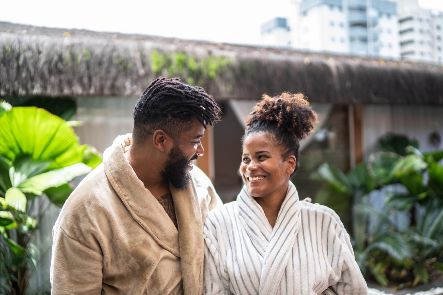 A couple wearing robes looking at each other as they share a trip to the spa.
